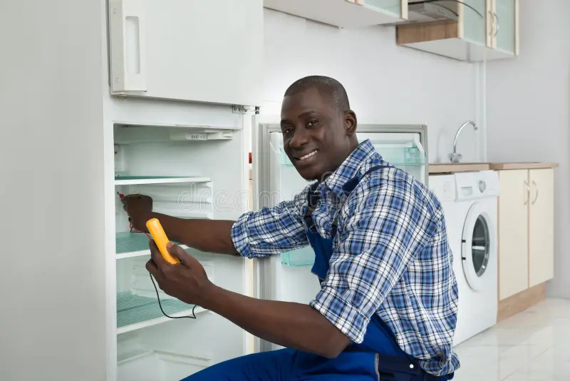 1753379520-technician-repairing-refrigerator-appliance-happy-african-kitchen-room-56306322.jpg