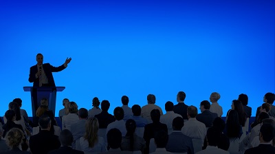 1754471816-corporate-businessman-giving-presentation-large-audience.jpg