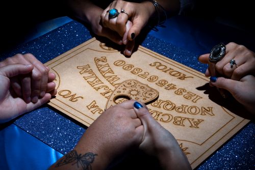1755593992-high-angle-people-using-ouija-board-together.jpg